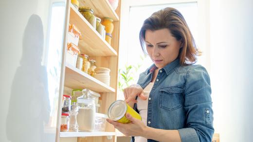Woman checking label on canned food